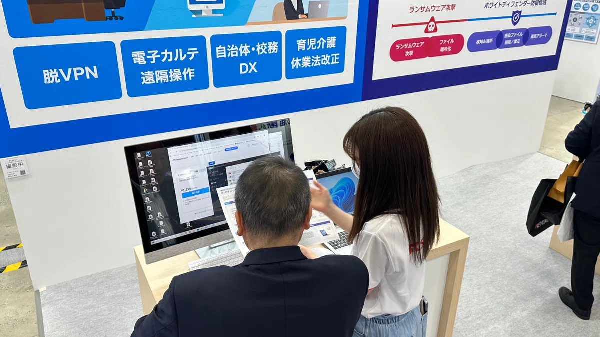 Japan DX Week 2026 春のRSUPPORTブースにて、RemoteView（リモートビュー）のデモ画面を使い、脱VPNや遠隔操作について説明する様子。